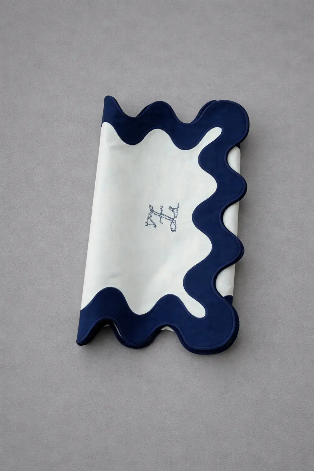 Chemin de table bleu brodé plié, détail de la finition ondulée